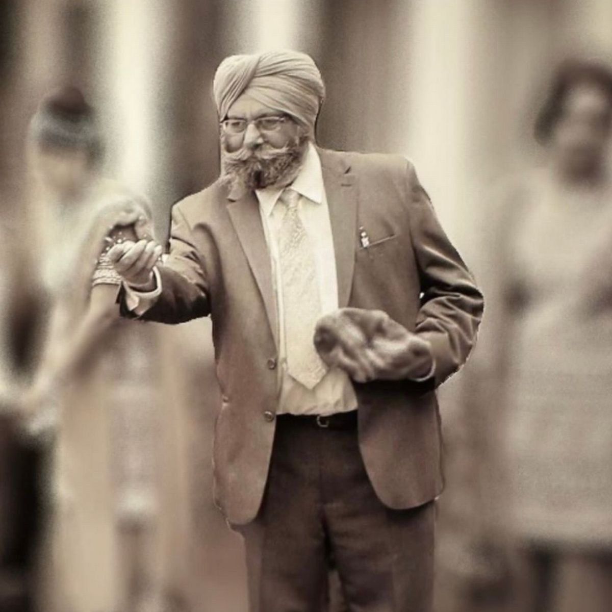 Elderly Sikh man in turban and suit dancing joyfully at a wedding, holding hands with a bride in traditional attire.