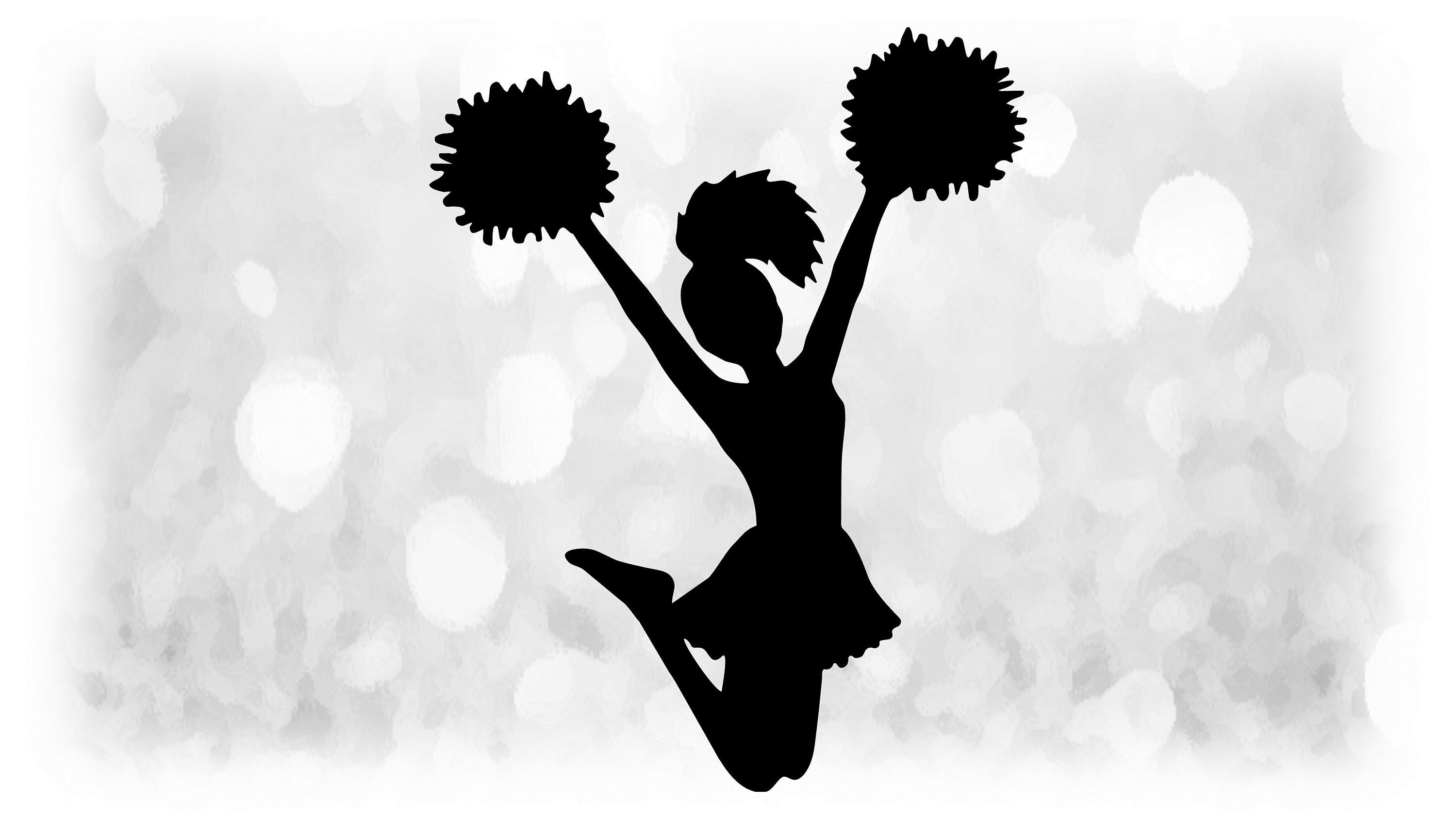 Silhouette of a cheerleader jumping with pom-poms raised against a bokeh background.