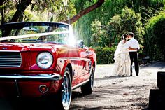 Red vintage Ford Mustang convertible with wedding couple in garden background