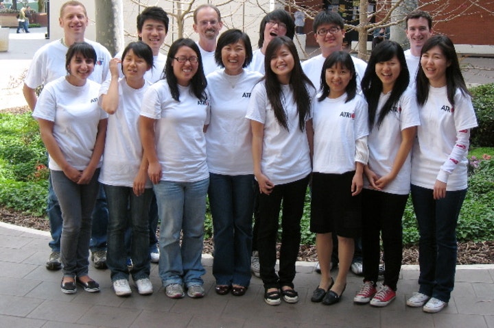 Group of smiling students and mentors in matching white "ATR" t-shirts posing outdoors on campus.