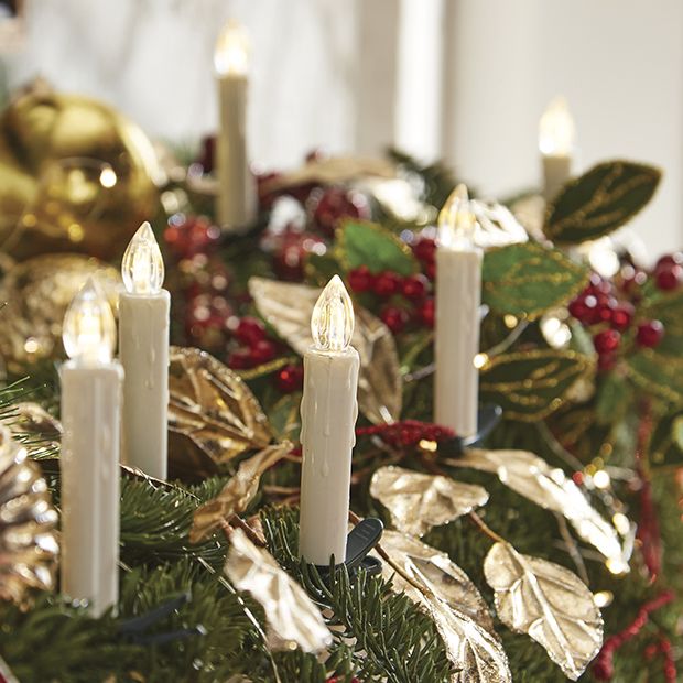 Festive holiday centerpiece with white LED flameless candles, gold leaves, red berries, and greenery.