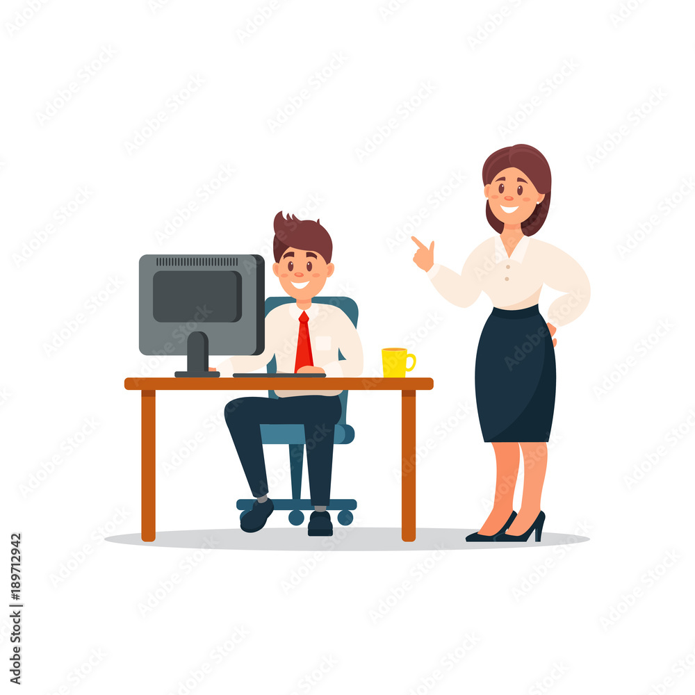 A smiling businesswoman pointing while a man works at a computer desk in an office setting.