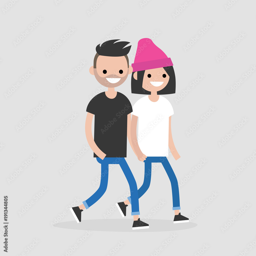 Smiling young couple walking together, man in black tee and jeans, woman in white tee, blue jeans, and pink beanie.