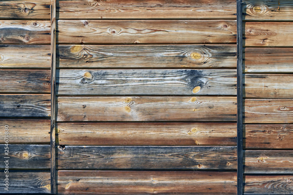 Weathered horizontal wooden planks with natural grain, knots, and aged patina, framed by vertical metal strips.