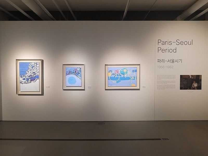 Three framed abstract paintings from the Paris-Seoul Period (1956-1962) displayed in a gallery with bilingual wall text.