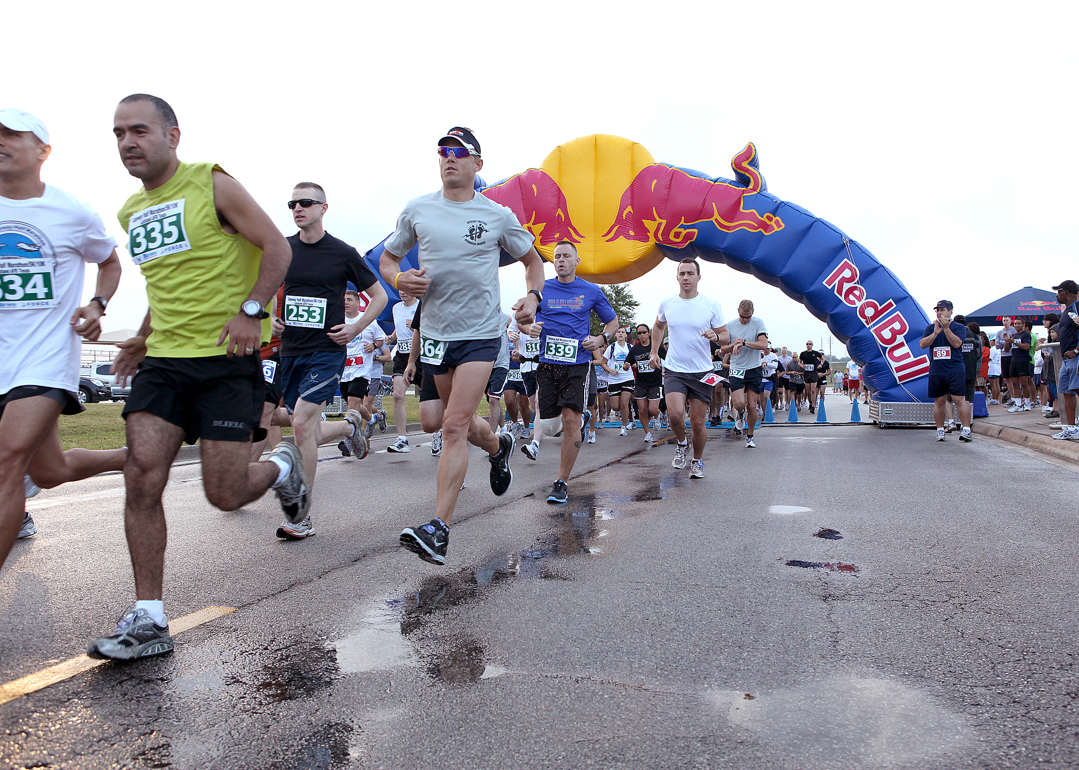 Runners crossing the finish line under a Red Bull inflatable arch during a marathon event.