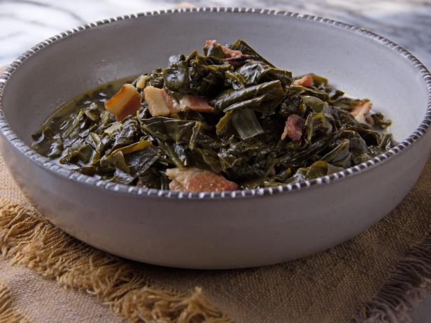 A rustic bowl of Southern-style cooked collard greens with ham hock, served on a woven cloth.