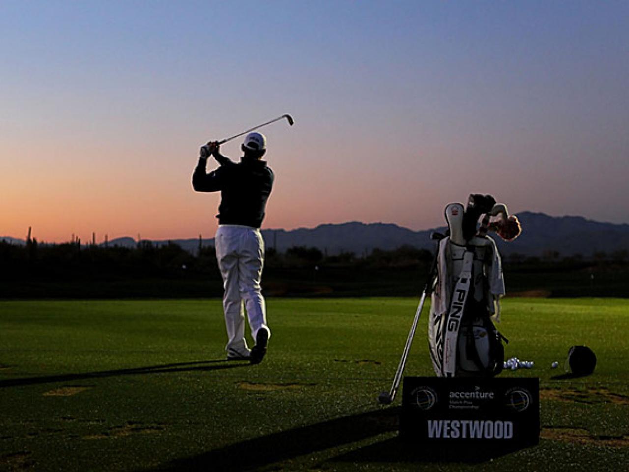 Golfer mid-swing at sunset with PING bag and Westwood signage on a desert course.