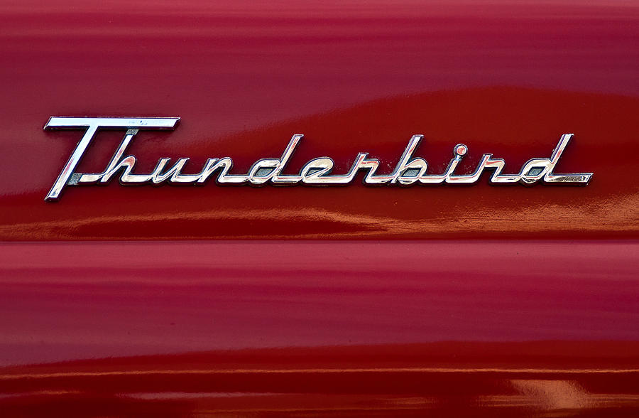 Chrome "Thunderbird" emblem on glossy red vintage car body.