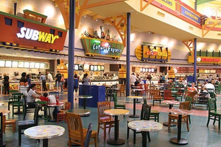 Busy indoor food court with Subway, Lotus Express, and Cajun Grill stalls; patrons dining at colorful tables and chairs.