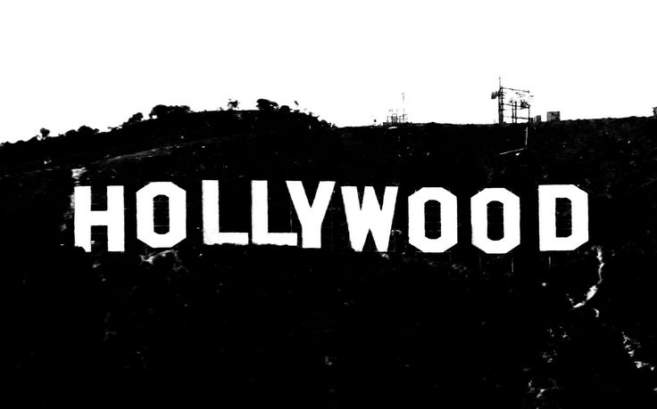 Iconic Hollywood sign on a hillside in black-and-white, with communication towers visible in the background.