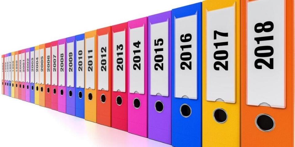 Colorful file folders labeled with years from 1998 to 2018, arranged in a receding line on white background.