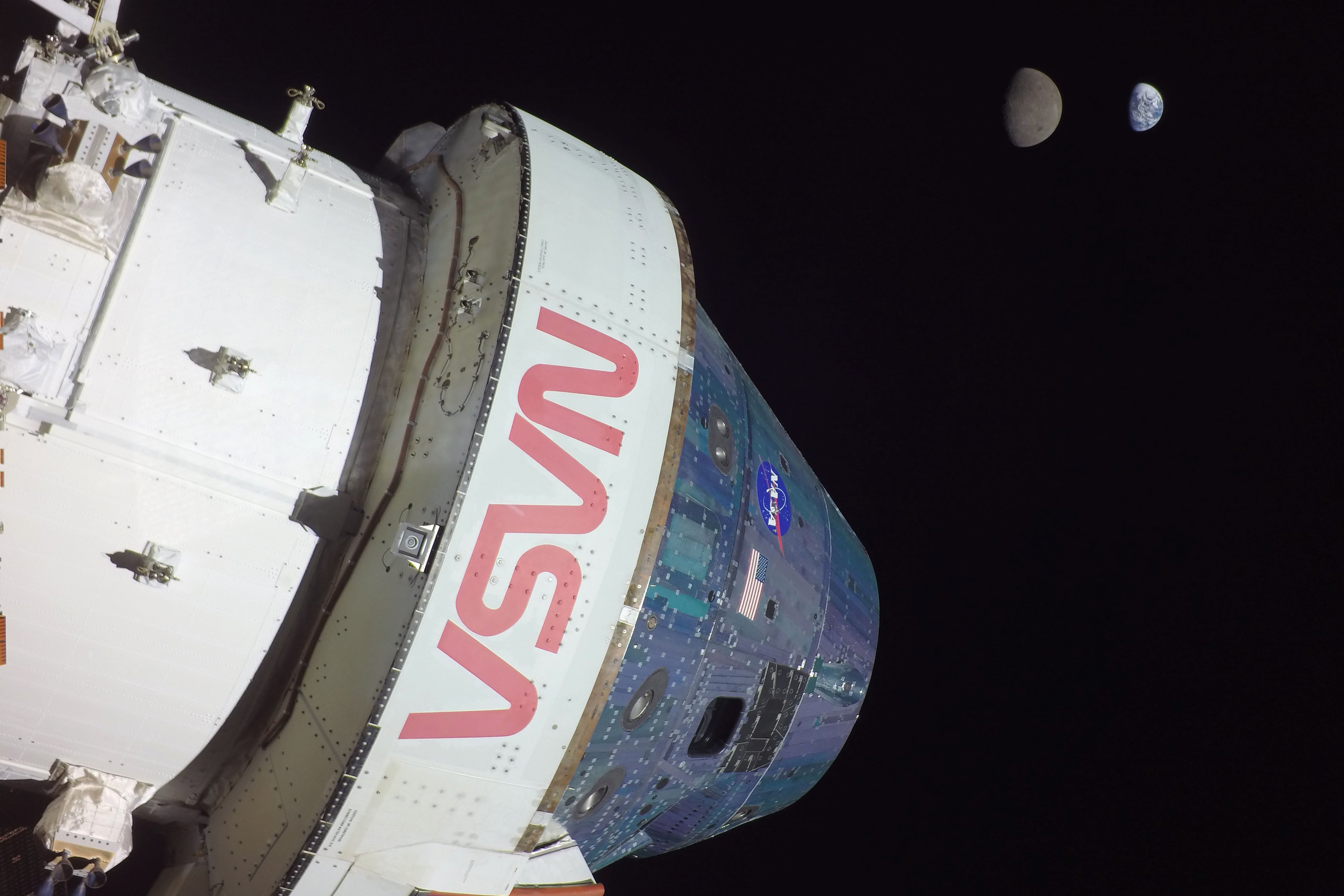 NASA spacecraft docked to ISS with Moon and Earth visible in background space view.