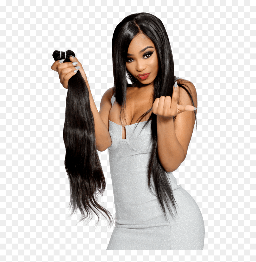Woman in silver dress holding a bundle of long black hair extensions, posing confidently with a finger heart gesture.