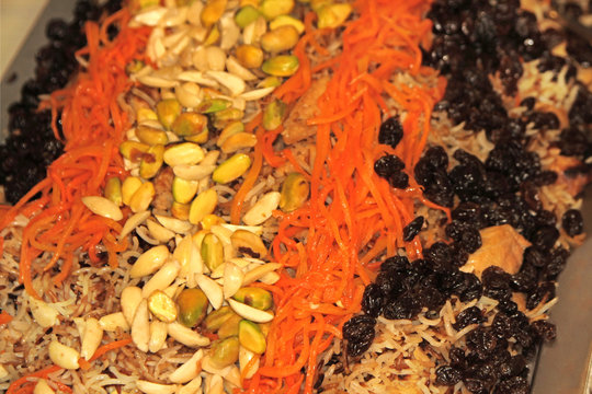 Colorful Persian rice pilaf topped with shredded carrots, pistachios, almonds, and raisins.