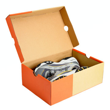 Open orange and beige shoebox revealing a pair of gray, black, and yellow athletic sneakers inside.