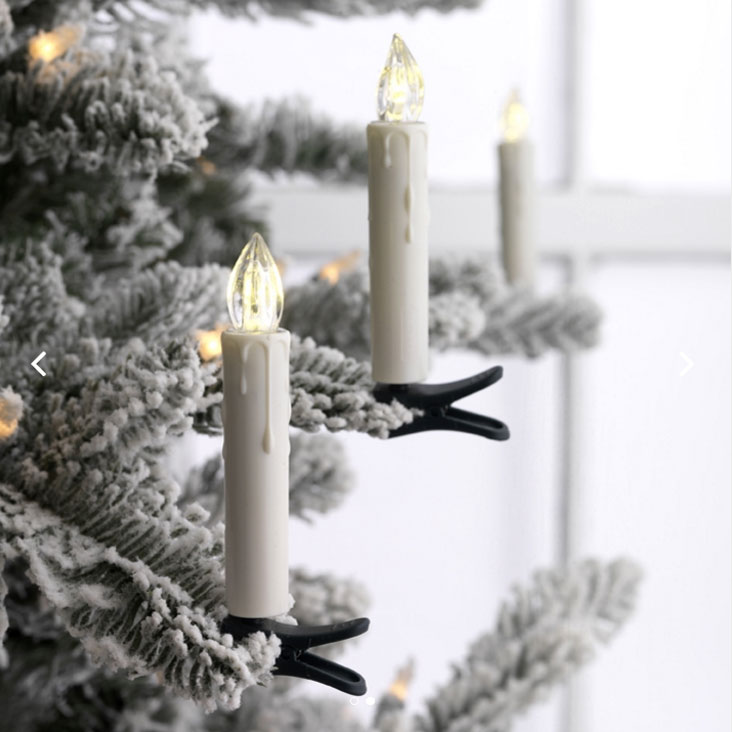 Flocked Christmas tree branch with white LED candle clip-on lights glowing softly.
