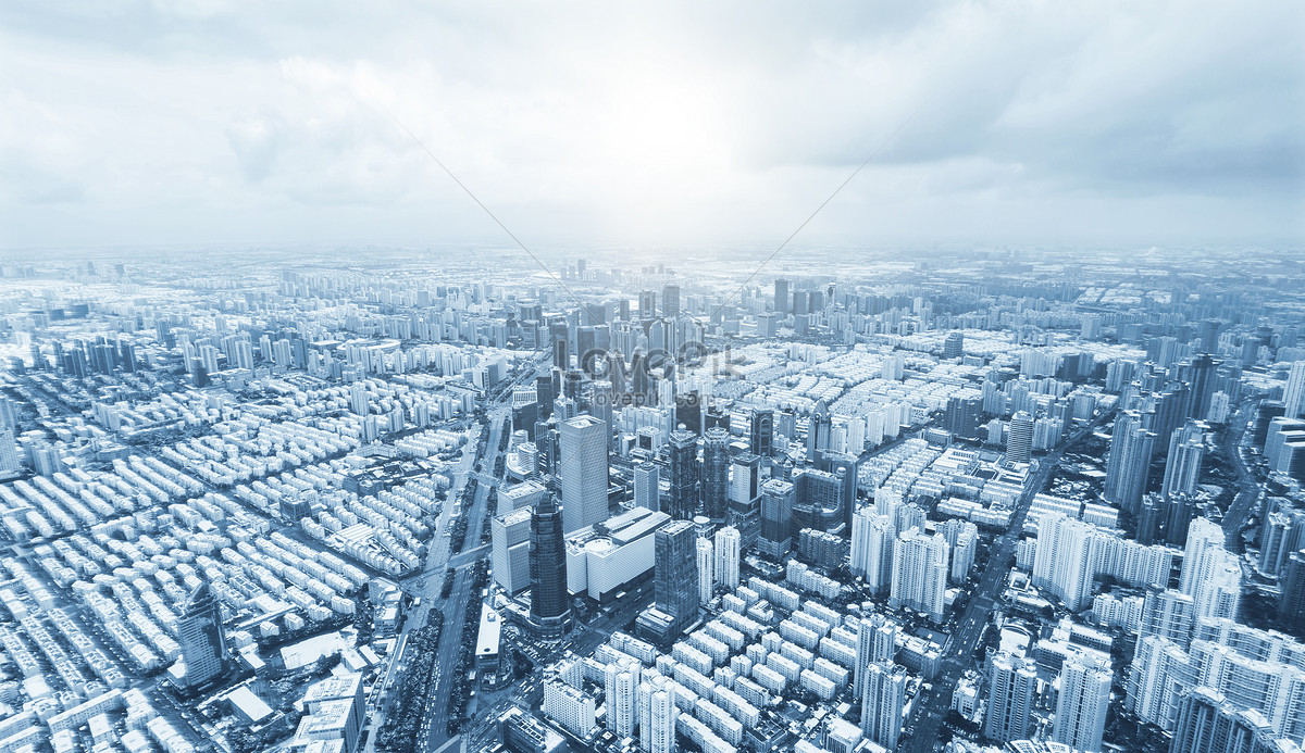 Aerial view of a sprawling modern metropolis with dense high-rise buildings under a cloudy sky.