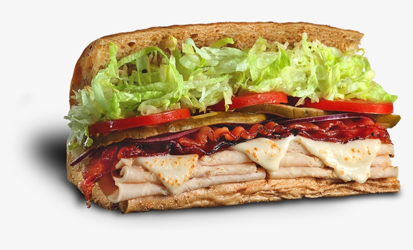 A hearty sub sandwich with turkey, melted cheese, bacon, red onions, pickles, tomato, and lettuce on toasted bread.