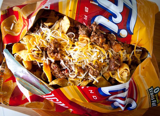 Frito Pie in an open bag: corn chips topped with chili, shredded cheese, and onions.