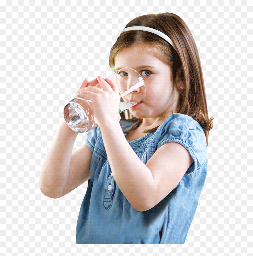 Young girl in blue dress drinking water from a clear glass, wearing a white headband.