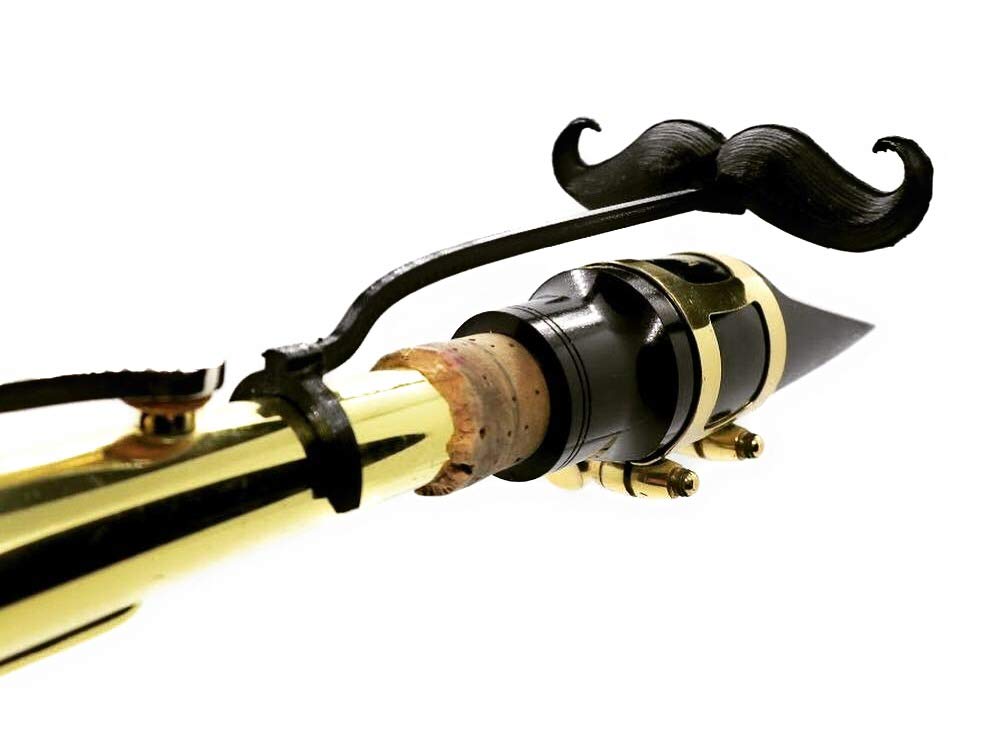 A brass woodwind instrument with a black mustache-shaped novelty attachment on its mouthpiece.
