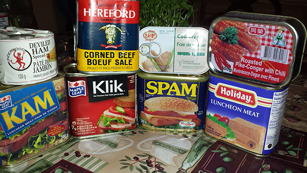 A collection of canned meats including SPAM, Klik, Hereford corned beef, KAM, Holiday luncheon meat, deviled ham, and foie gras.