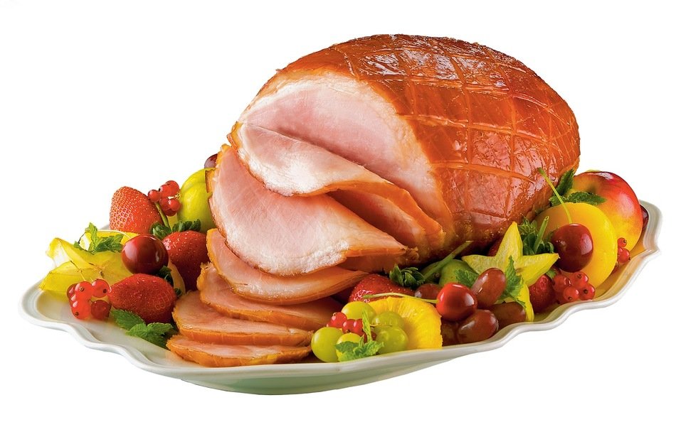 Glazed spiral-cut ham with fresh fruit garnish on a white platter.