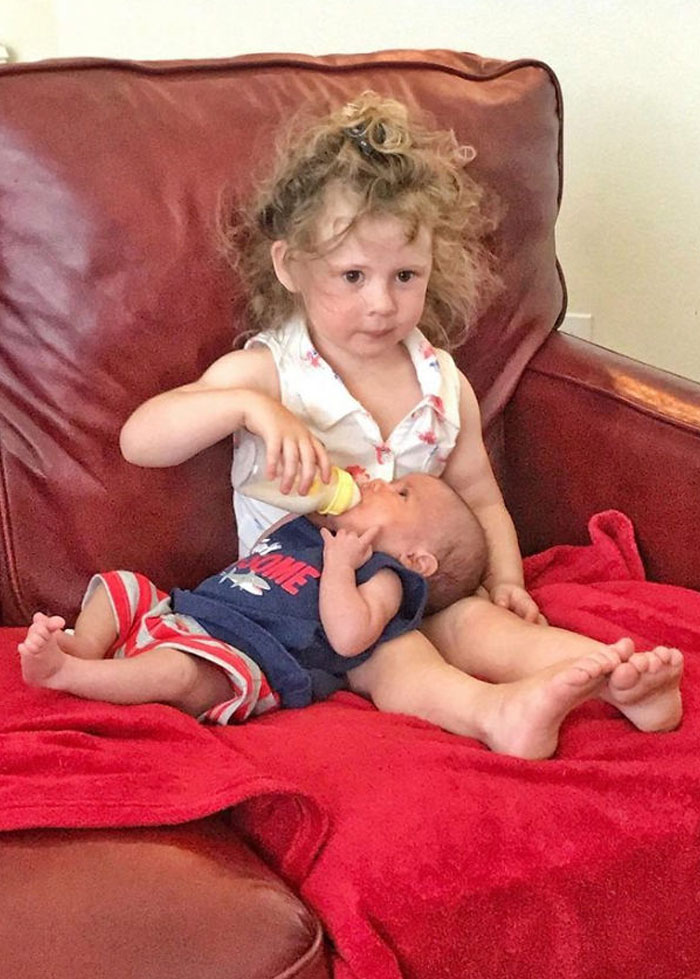 Adorable Sibling Moment: Toddler Feeding Baby Brother on Couch