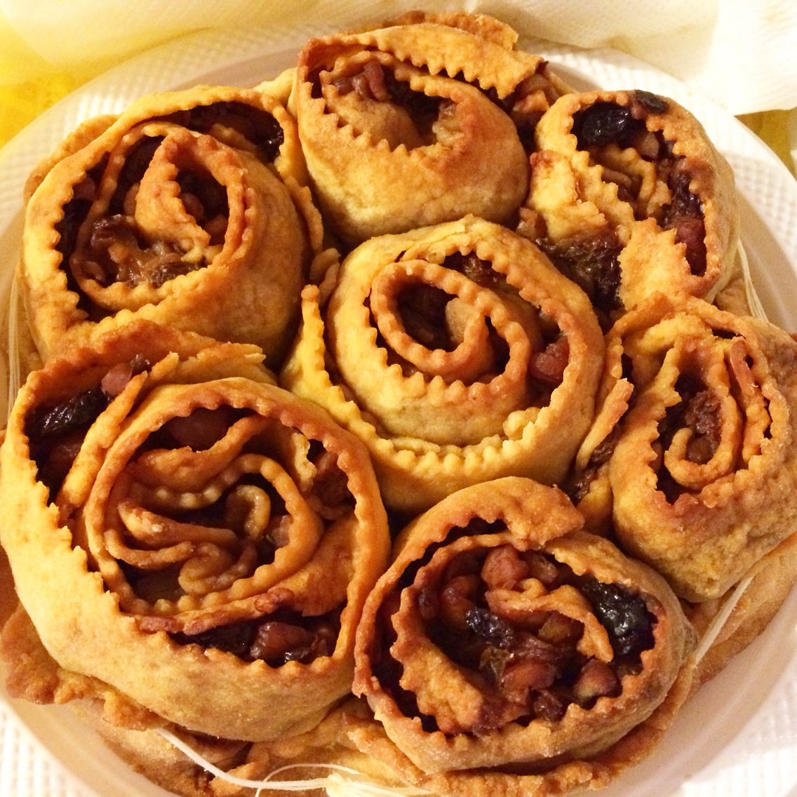 Golden spiral pastries filled with raisins and nuts, arranged on a white plate.