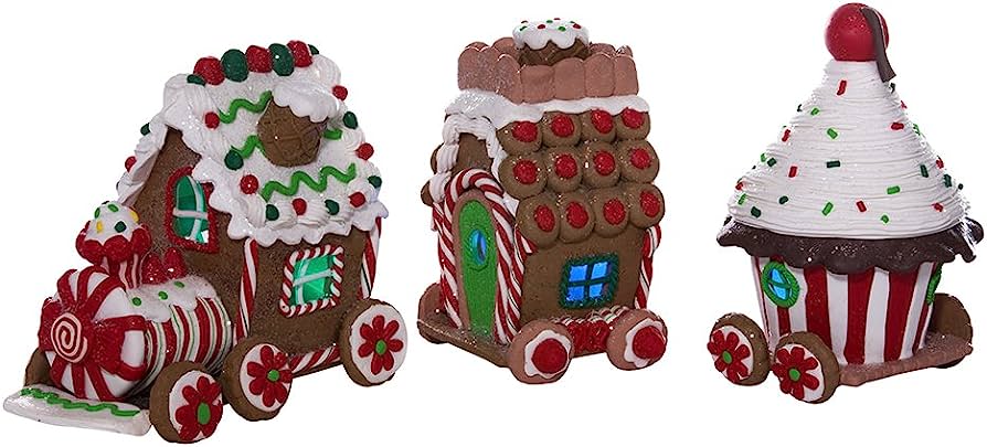 Three festive Christmas-themed ceramic figurines: a candy cane train, gingerbread house, and cupcake on wheels, decorated with icing and sprinkles.