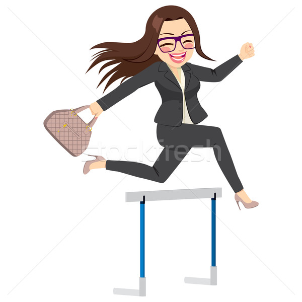 Businesswoman in suit and glasses joyfully leaping over a hurdle while holding a handbag.