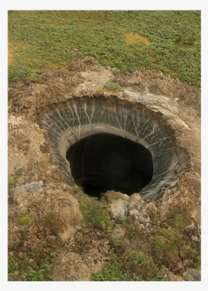 A deep, circular sinkhole in grassy terrain with exposed soil layers and a dark interior.
