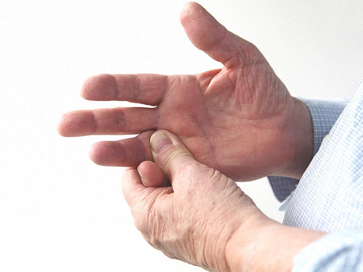 Older adult massaging the base of the thumb on their palm, indicating hand pain or arthritis.