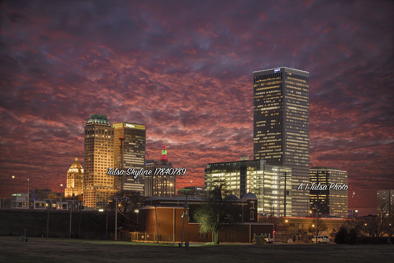 Tulsa skyline at dusk with vibrant red-purple clouds and illuminated skyscrapers, including the BOK Tower and SpiritBank Center.