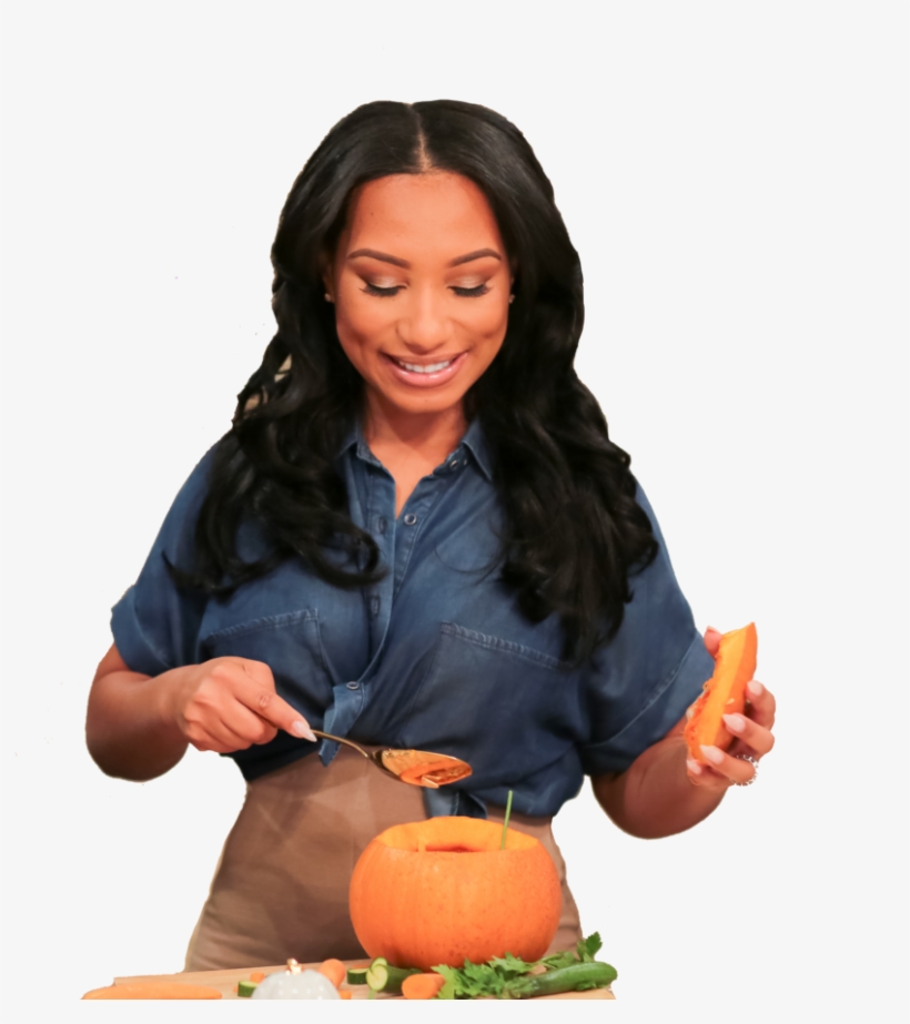Woman in denim shirt scooping pumpkin flesh with spoon, preparing a fall recipe.