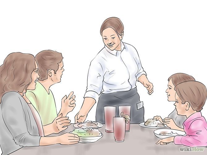 A smiling waitress serves food to a family of four at a restaurant table.