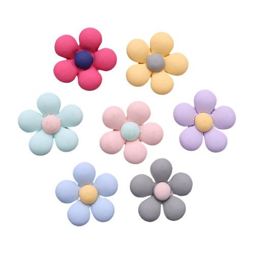 Seven colorful clay flower charms in pastel and bright hues with contrasting centers, arranged on white background.