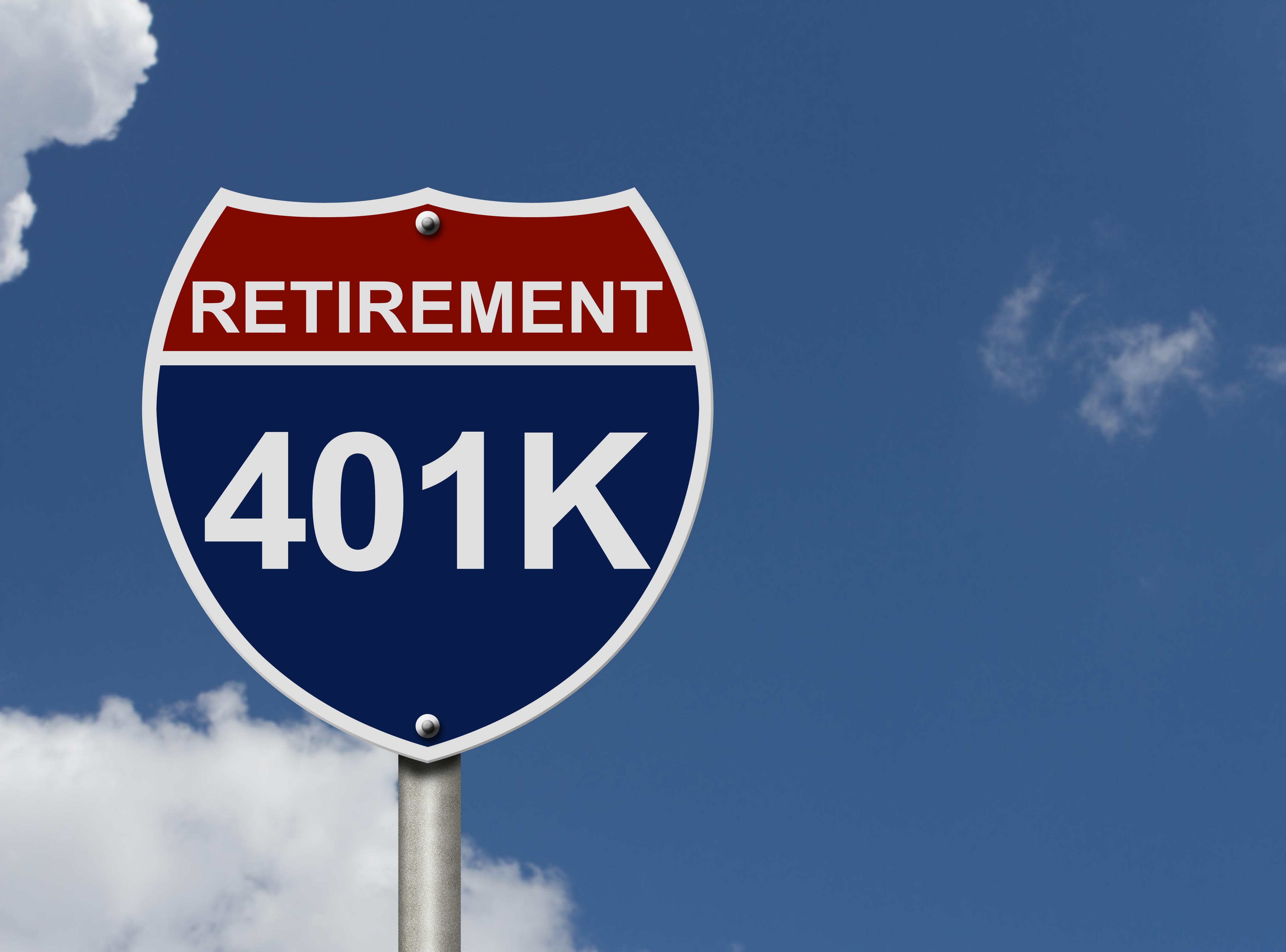 Highway-style sign reading "RETIREMENT" above "401K" against a blue sky with clouds.