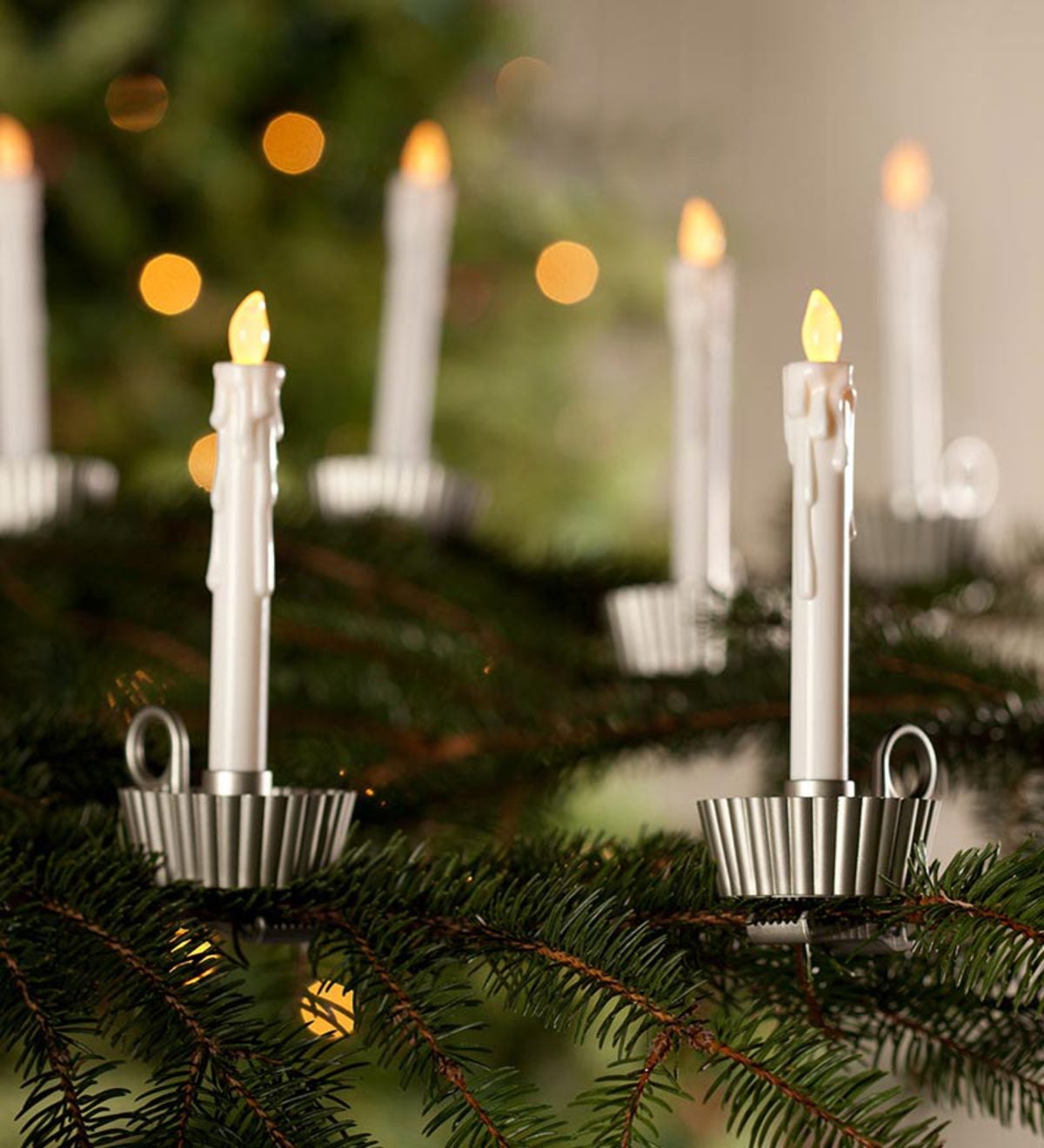 LED candle clips with realistic flame effect attached to evergreen branches, creating warm holiday ambiance.