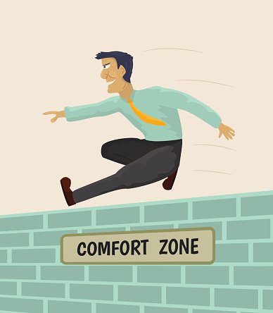 A man in business attire leaps over a brick wall labeled "Comfort Zone," symbolizing stepping beyond familiar boundaries.