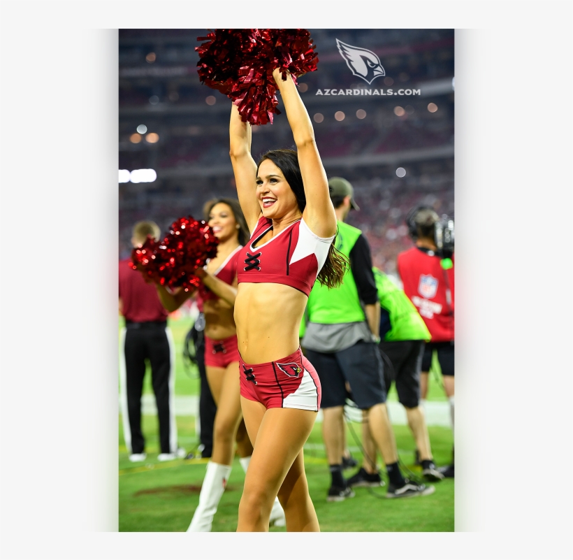 Arizona Cardinals cheerleader performing with red pom-poms on the field during a game.