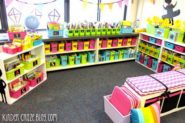 Bright, organized elementary classroom with colorful labeled bins, bookshelves, and reading nook.