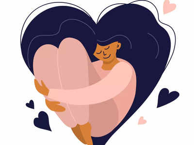 A person with long dark hair hugs their knees inside a large heart, surrounded by small hearts-symbolizing self-love and emotional comfort.