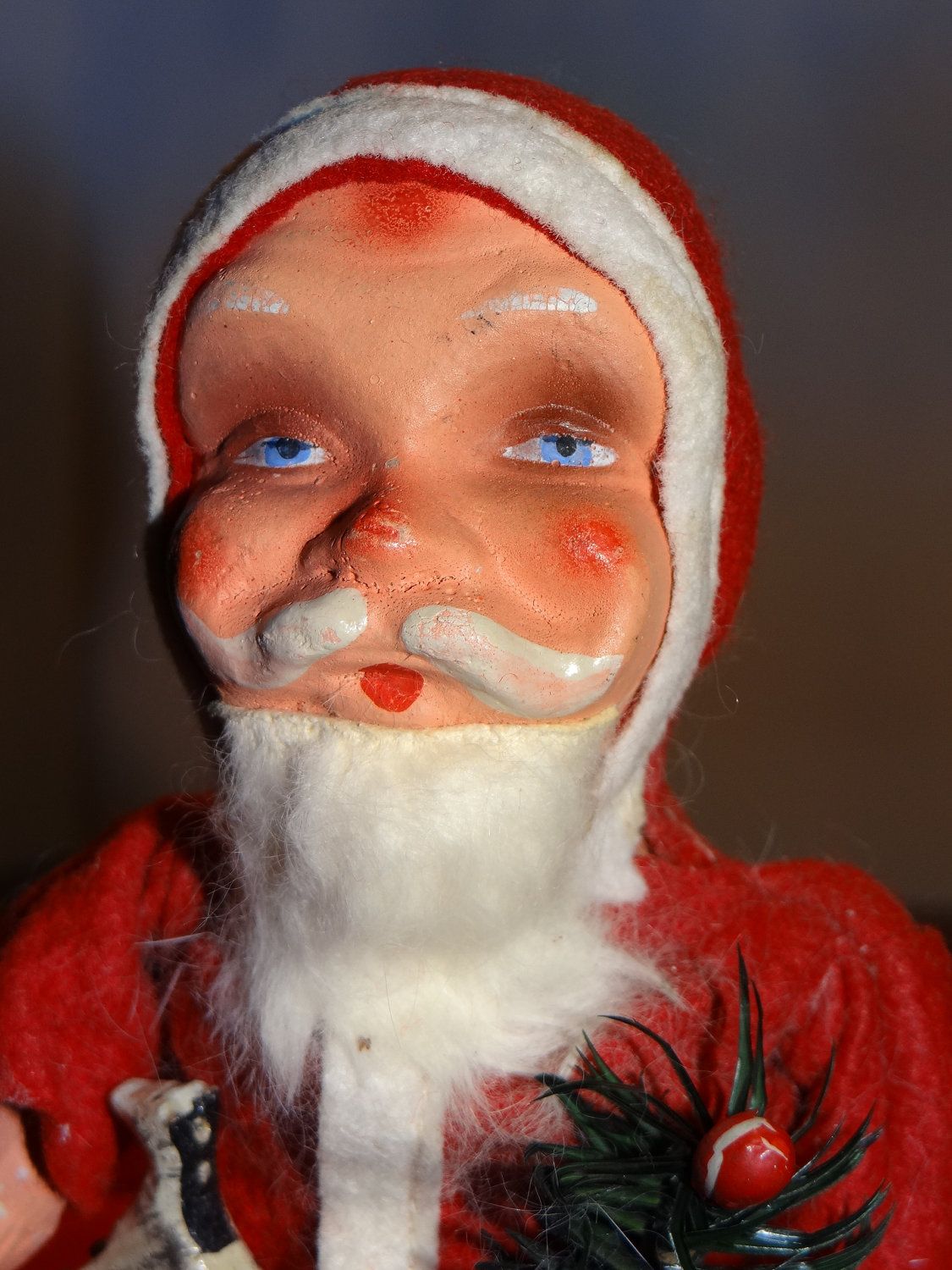 Vintage papier-mâché Santa Claus figurine with painted blue eyes, rosy cheeks, and white beard, wearing red felt suit and hat.