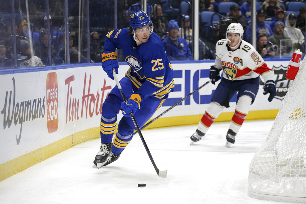 Buffalo Sabres player #25 in blue jersey controls puck near net as Florida Panthers defender #19 pursues during NHL game.