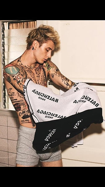 Tattooed model holding Balenciaga underwear in a tiled bathroom setting.