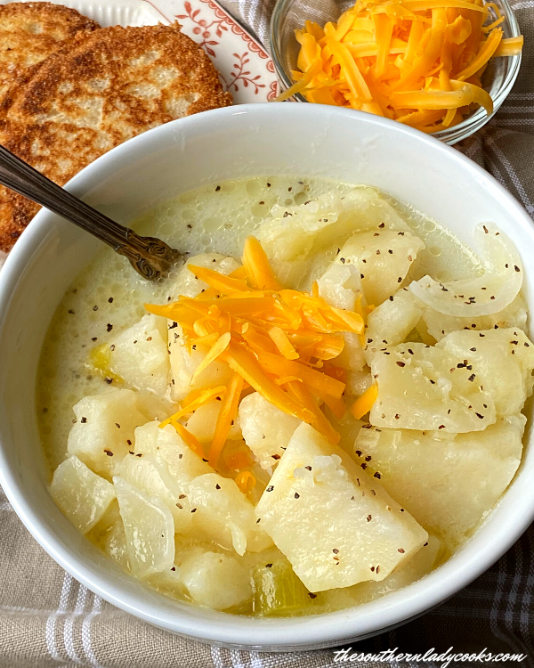 Creamy potato soup with shredded cheddar, black pepper, and toasted bread on the side.