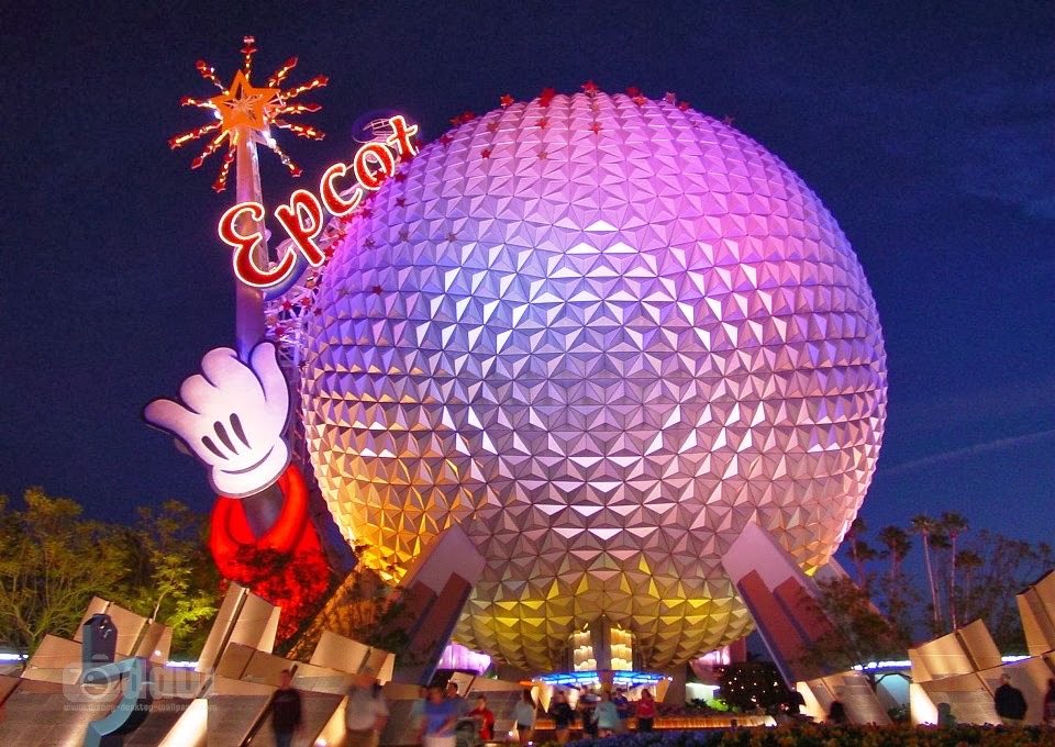 Epcot’s iconic geodesic sphere, Spaceship Earth, illuminated at night with the Epcot sign and Mickey hand sculpture in foreground.