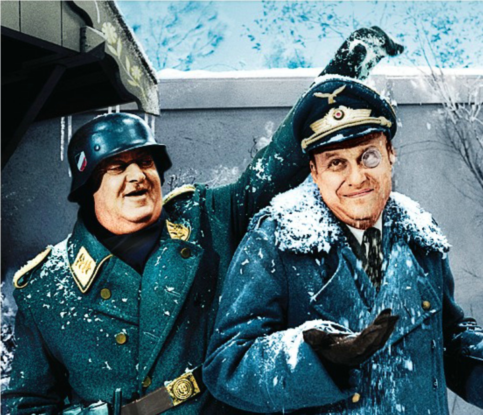 Two men in WWII-era German military uniforms posing playfully in snow, one with monocle and raised arm.